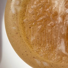 Load image into Gallery viewer, Extreme closeup of glycerin face soap with an embossed tree design and embedded brown specks of rhassoul clay that can be seen.
